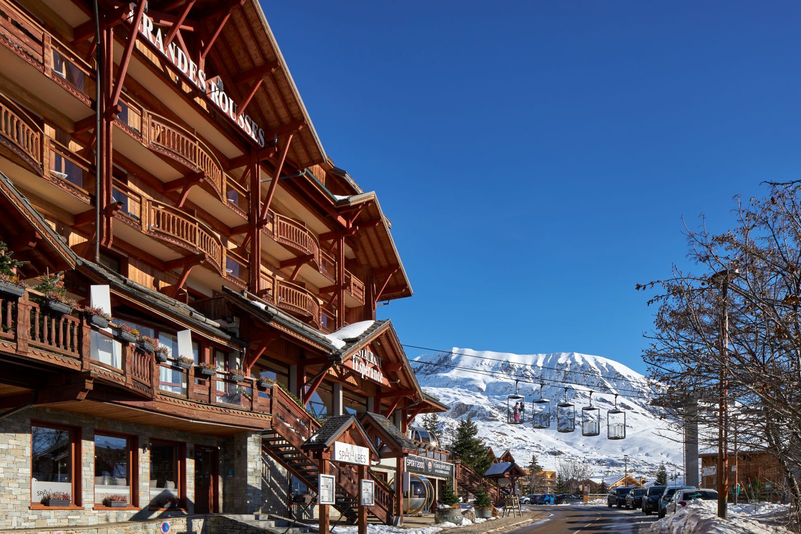 Grandes Rousses Hotel & Spa Alpe d'Huez - Hotel entrance with ski lifts and mountains