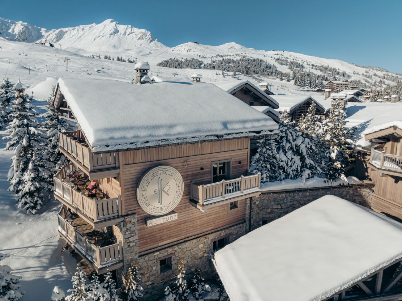 Hotel Le K2 Altitude Courchevel - Ariel view of hotel exterior with trees mountains and snow