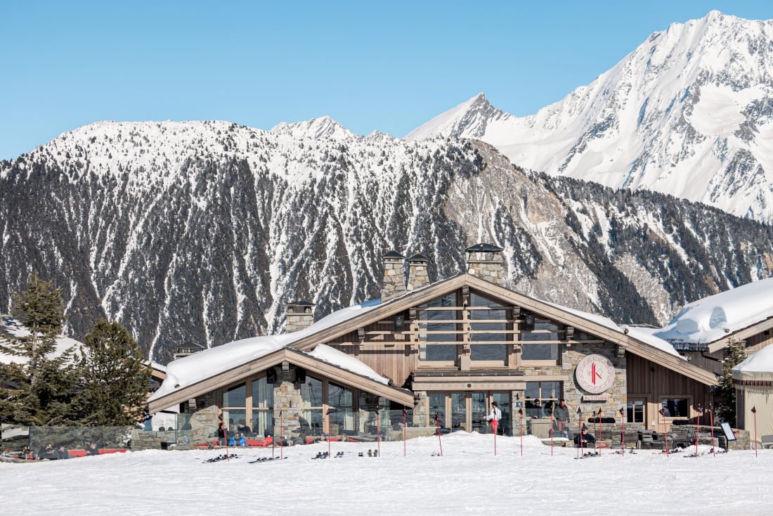 Hotel Le K2 Altitude Courchevel - hotel exterior with skiers and mountains