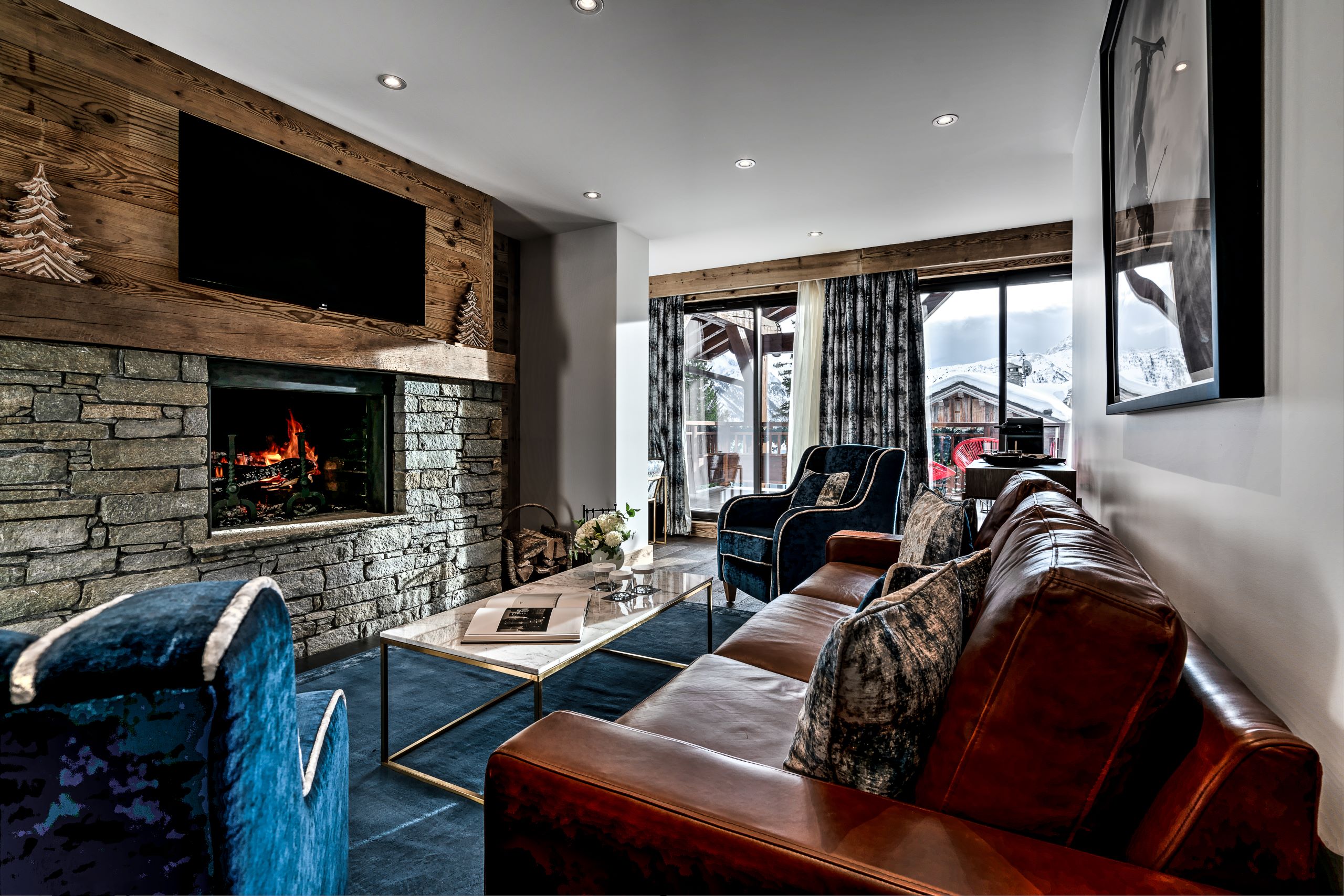 Hotel La Sivolière Courchevel - Spacious living room with sofa chairs coffee table tv fire place and balcony