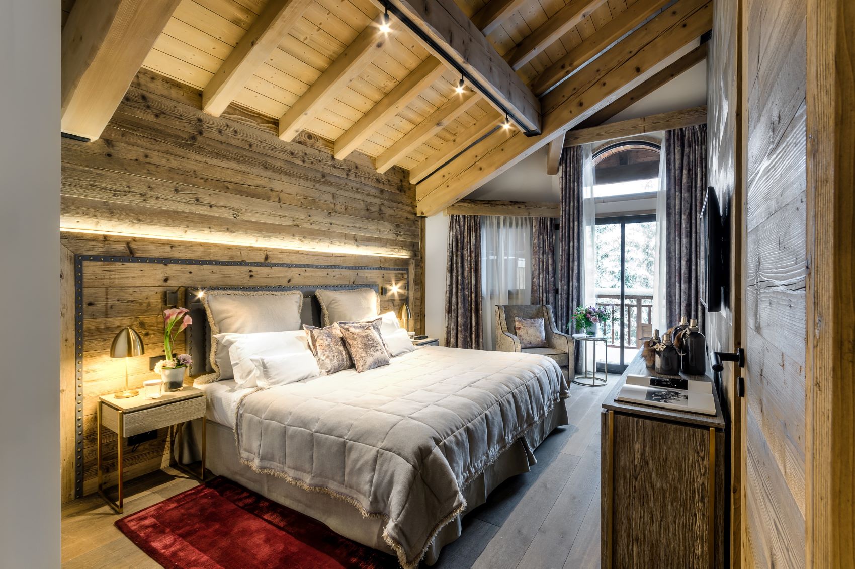 Hotel La Sivolière Courchevel - Large king size bedroom with wood panelling seating area TV and private balcony