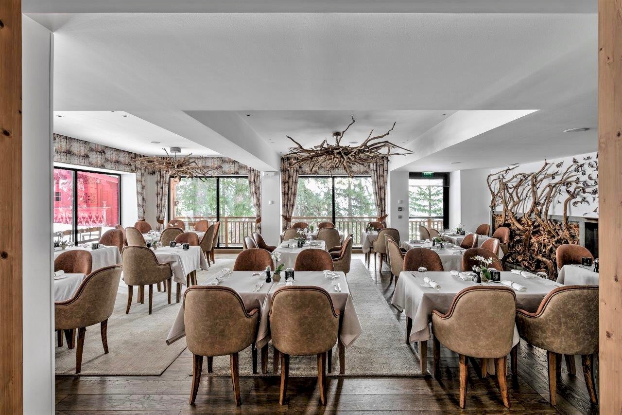 Hotel La Sivolière Courchevel - Bright restaurant dining room with lots of windows showing forest views