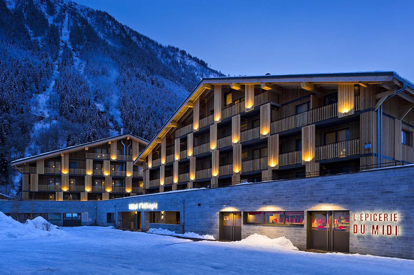 Hotel Héliopic Chamonix - Hotel exterior lit up at night with forest and mountain views