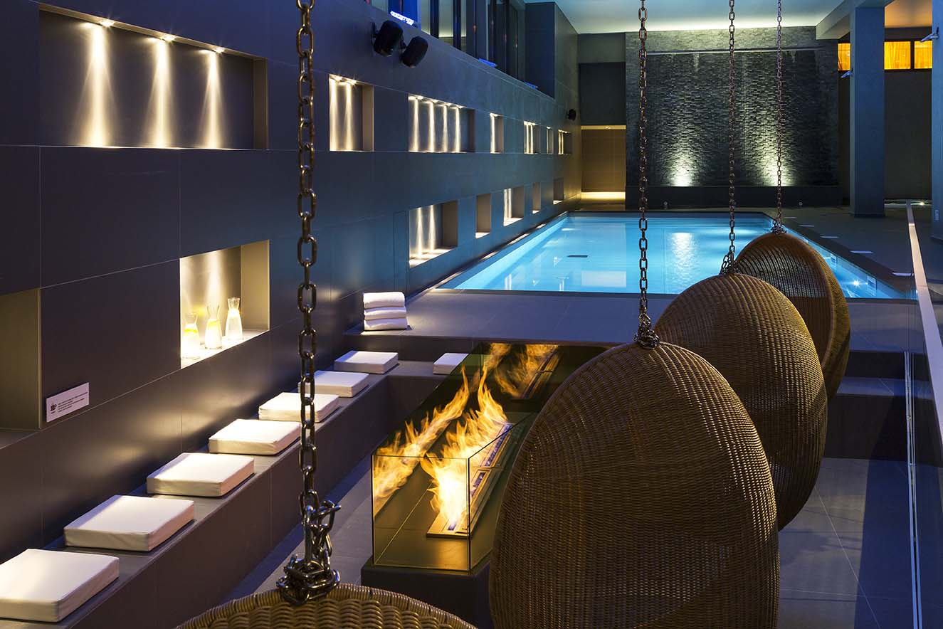 Hotel Héliopic Chamonix - Relaxing indoor pool area with egg shaped seating around a fire
