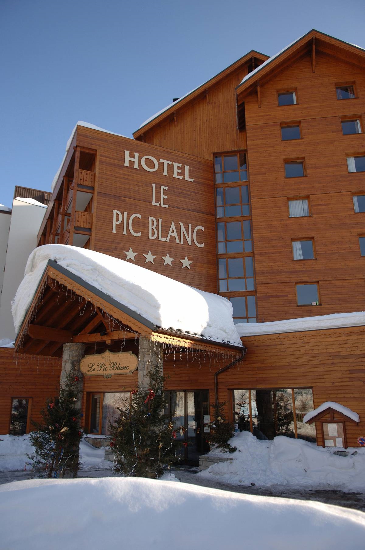 Hotel Le Pic Blanc Alpe d'Huez - Hotel exterior with snow and Christmas trees